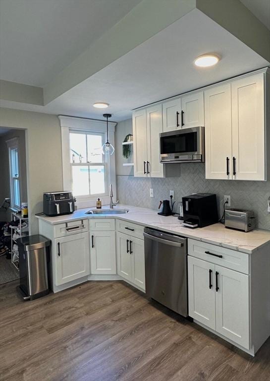 kitchen featuring appliances with stainless steel finishes, dark wood-style flooring, a sink, and white cabinetry