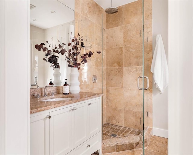 bathroom with a stall shower, vanity, and baseboards