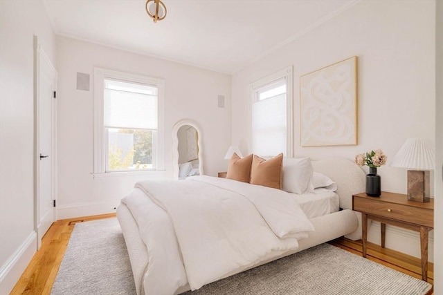 bedroom featuring light wood-style floors, baseboards, and crown molding