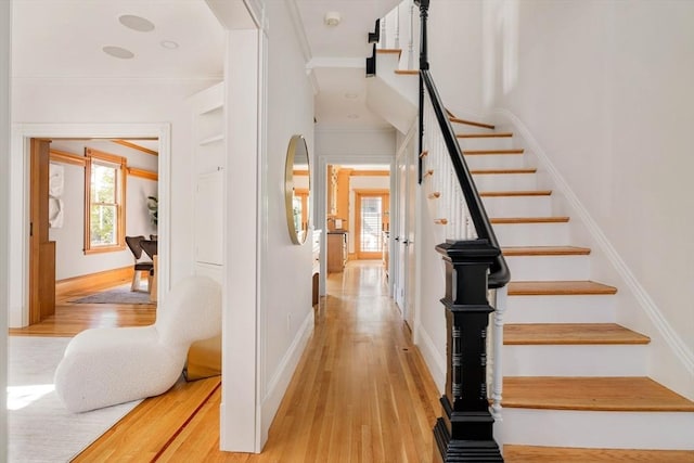 stairs featuring crown molding, baseboards, and wood finished floors