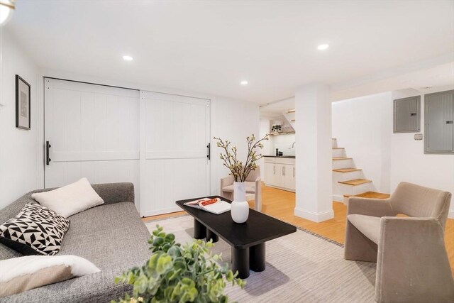 living room featuring light wood-type flooring, electric panel, stairway, and recessed lighting