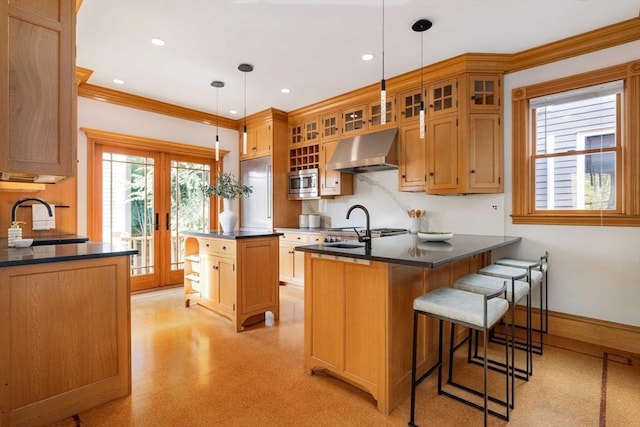 kitchen featuring dark countertops, stainless steel microwave, a sink, a peninsula, and under cabinet range hood