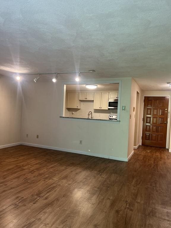 9 Broadway Unit 210, Saugus, MA 01906 - unfurnished living room featuring dark wood-type flooring, track lighting, and a textured ceiling