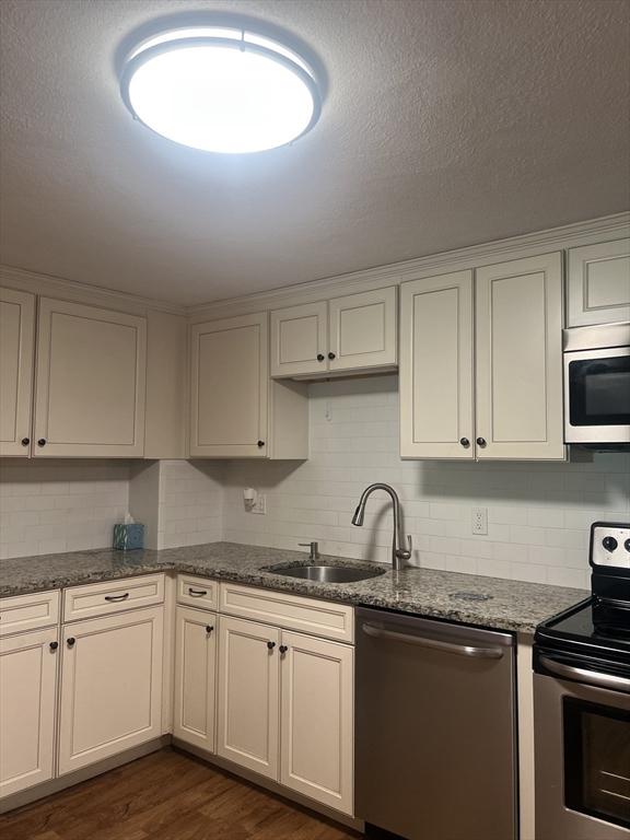 9 Broadway Unit 210, Saugus, MA 01906 - kitchen with stainless steel appliances, tasteful backsplash, dark wood-style flooring, and dark stone counters