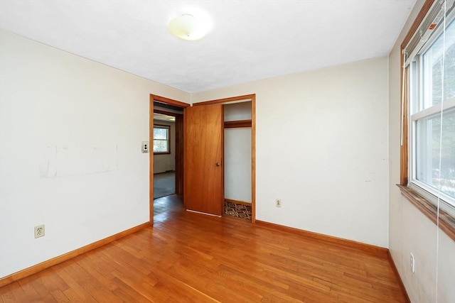 unfurnished bedroom with multiple windows and hardwood / wood-style flooring