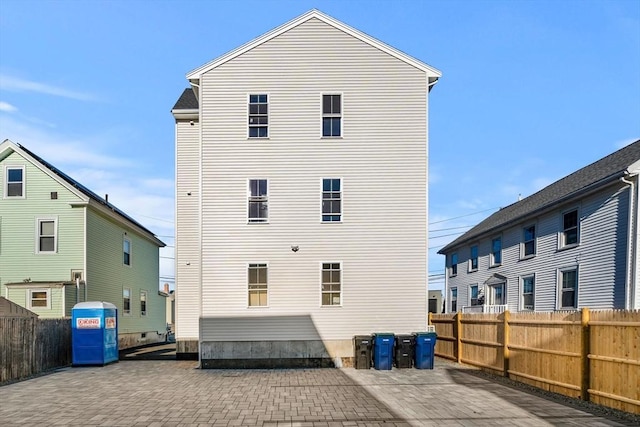 rear view of house with a fenced backyard and a patio