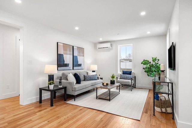 living room featuring light wood finished floors, baseboards, an AC wall unit, and recessed lighting