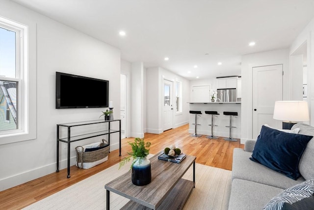 living area with light wood-style floors, baseboards, and recessed lighting