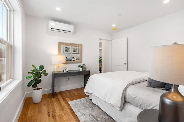 bedroom featuring baseboards, a wall mounted air conditioner, wood finished floors, and recessed lighting