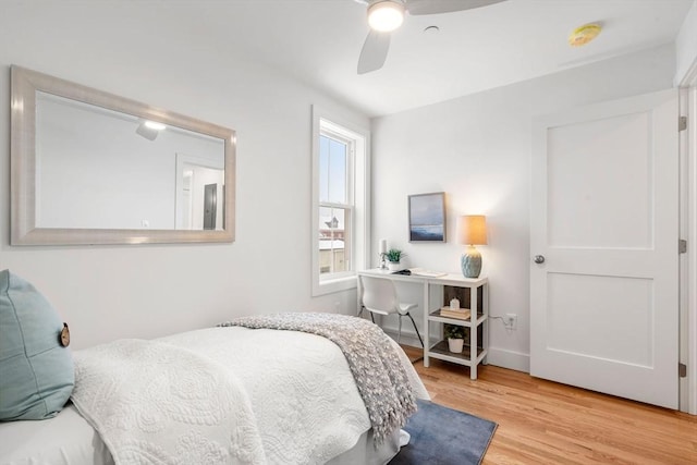 bedroom with ceiling fan, wood finished floors, and baseboards