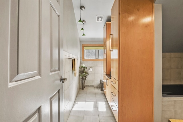 bathroom with a bathtub, tile walls, tile patterned flooring, and toilet