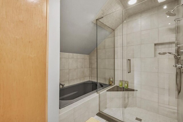 bathroom with shower with separate bathtub and tile walls