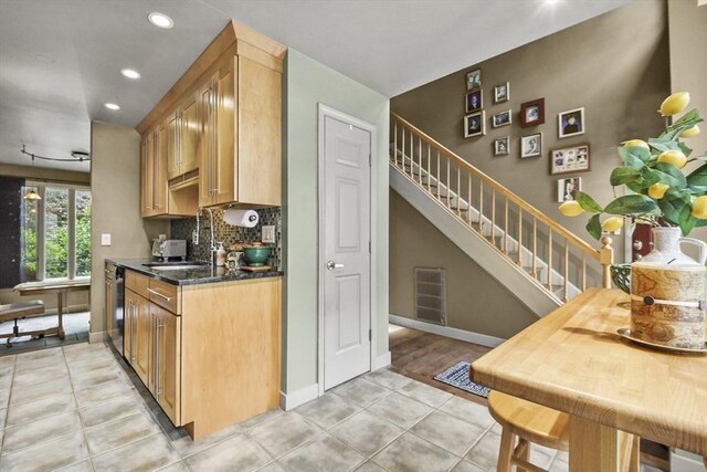 kitchen with sink, light tile patterned floors, backsplash, dishwasher, and dark stone counters