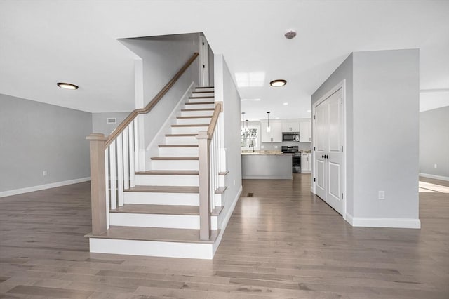 stairway with sink and wood-type flooring