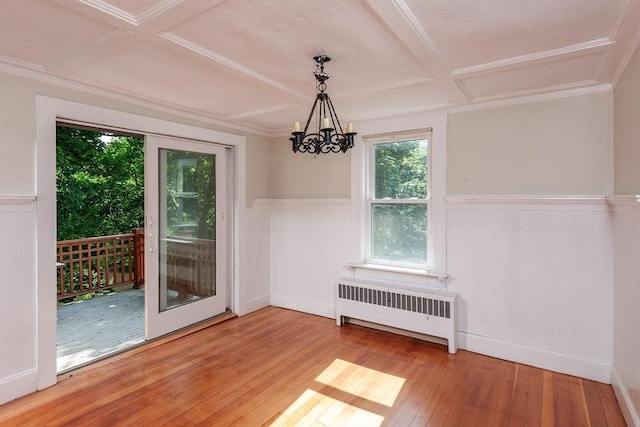 unfurnished dining area featuring a wainscoted wall, radiator heating unit, wood-type flooring, and coffered ceiling