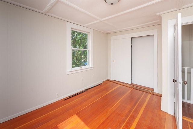 unfurnished bedroom with hardwood / wood-style floors, baseboards, and a closet