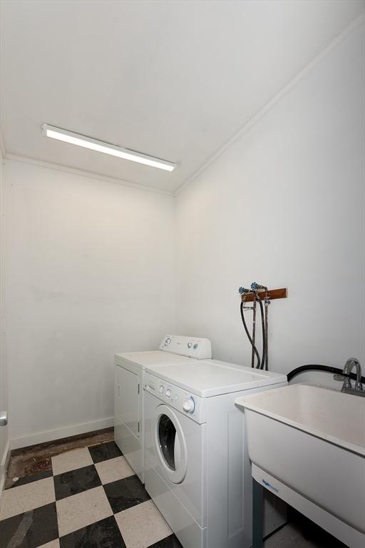 washroom with tile patterned floors, a sink, separate washer and dryer, baseboards, and laundry area