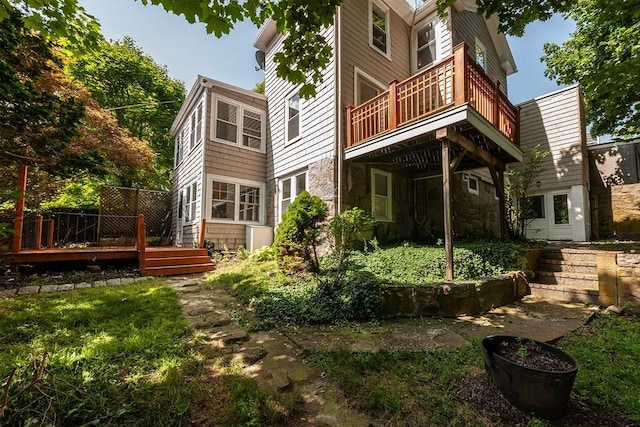 rear view of property with stone siding and a wooden deck