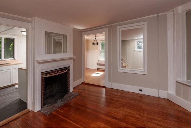 unfurnished living room with a fireplace with flush hearth, radiator, dark wood-style flooring, and a decorative wall