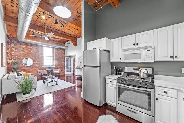 37 Millyard Unit 206, Amesbury, MA 01913 - kitchen with appliances with stainless steel finishes, brick wall, dark wood-style flooring, white cabinets, and wood ceiling