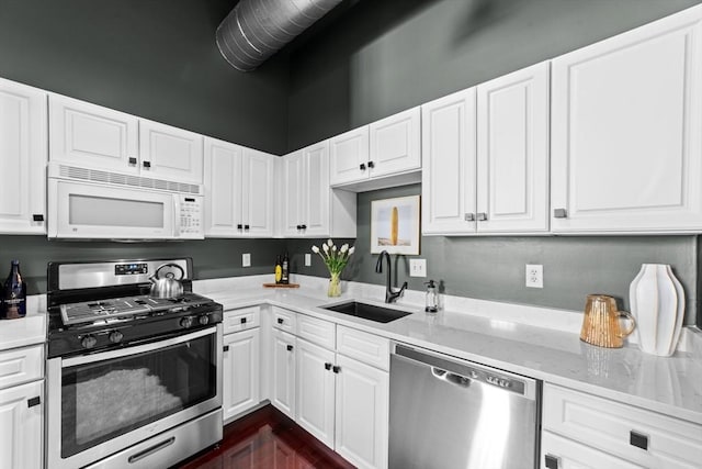 37 Millyard Unit 206, Amesbury, MA 01913 - kitchen featuring appliances with stainless steel finishes, a sink, white cabinets, and light stone countertops