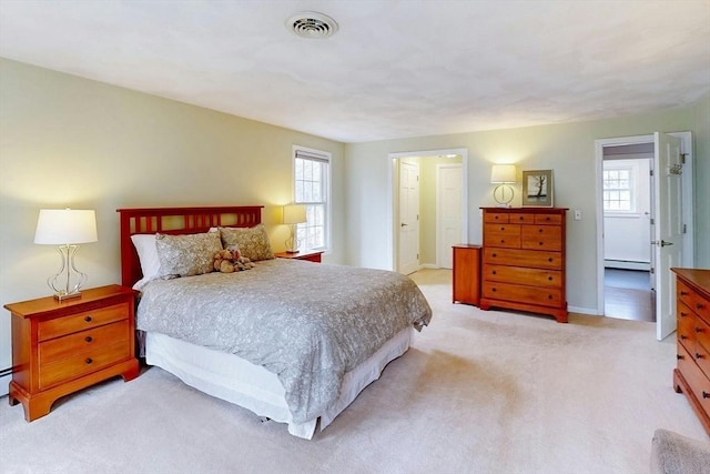 bedroom featuring visible vents, baseboards, baseboard heating, and light colored carpet