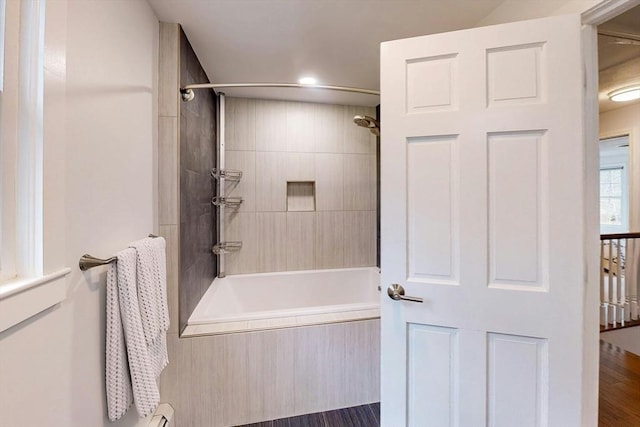 bathroom with wood finished floors, recessed lighting, and tiled shower / bath