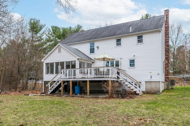 back of property featuring a chimney, a lawn, a deck, a sunroom, and stairs