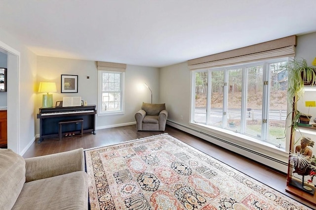 living area featuring baseboards, plenty of natural light, a baseboard heating unit, and wood finished floors