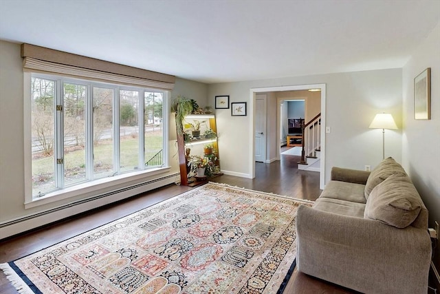 living area with baseboards, dark wood finished floors, baseboard heating, and stairway