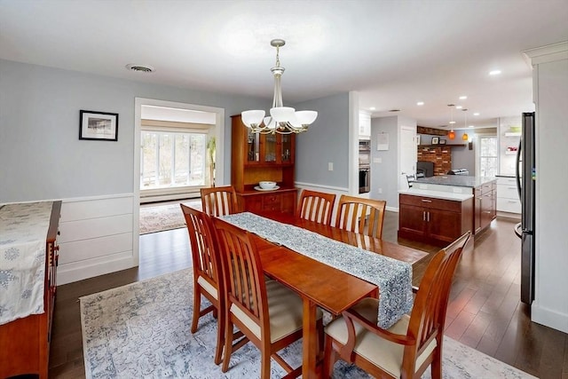dining space with an inviting chandelier, visible vents, dark wood-style floors, recessed lighting, and a baseboard heating unit