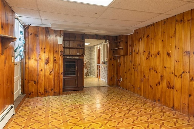 224 Palmer Rd, Monson, MA 01057 - empty room featuring wooden walls, baseboard heating, a fireplace, and a paneled ceiling
