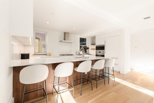 2A Milford St Unit 3, Boston, MA 02118 - kitchen with wall chimney range hood, light countertops, white cabinetry, visible vents, and modern cabinets