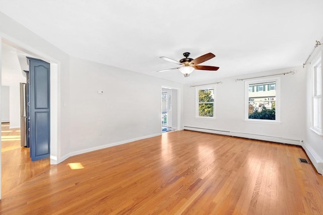 spare room with a baseboard radiator, light wood-type flooring, and ceiling fan