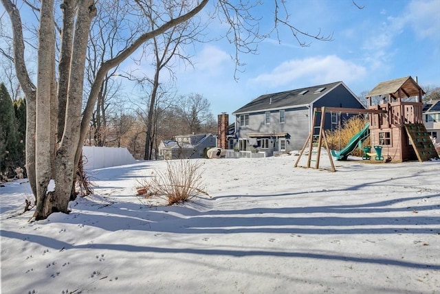 yard layered in snow featuring a playground