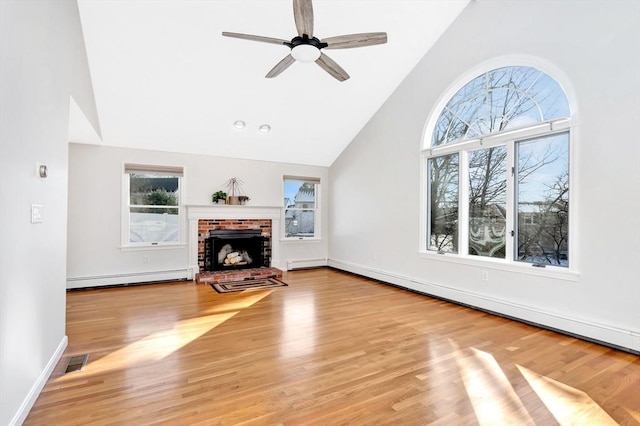 unfurnished living room featuring a baseboard radiator, light hardwood / wood-style flooring, high vaulted ceiling, a fireplace, and ceiling fan