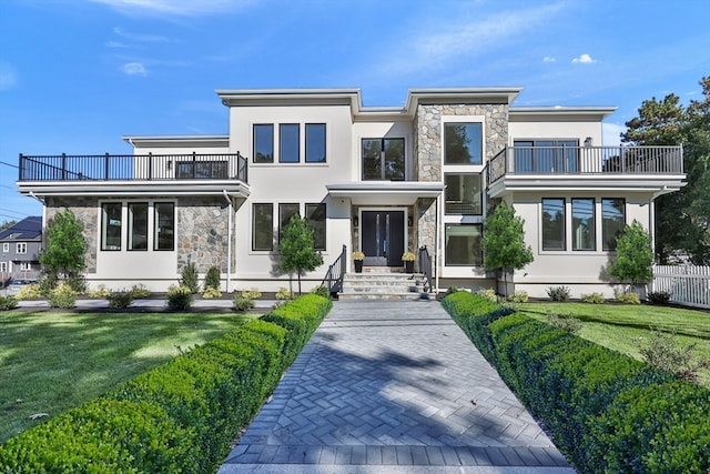 view of front of home with a balcony and a front yard