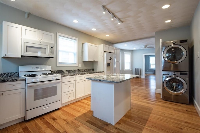 30 Partridge Ave, Somerville, MA 02145 - kitchen with white appliances, stacked washer and clothes dryer, rail lighting, radiator heating unit, and a kitchen island