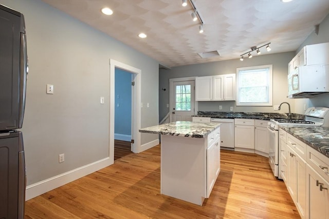 30 Partridge Ave, Somerville, MA 02145 - kitchen featuring white appliances, rail lighting, dark stone counters, white cabinets, and a center island