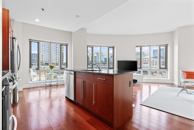 kitchen with dark hardwood / wood-style flooring, sink, a center island with sink, and appliances with stainless steel finishes