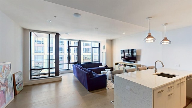 kitchen featuring a sink, floor to ceiling windows, hanging light fixtures, open floor plan, and light stone countertops