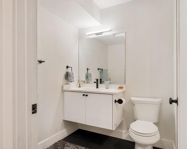 half bathroom with vanity, toilet, and baseboards