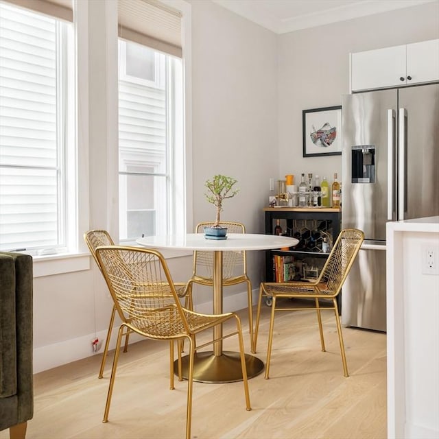 dining room with baseboards, light wood finished floors, and crown molding