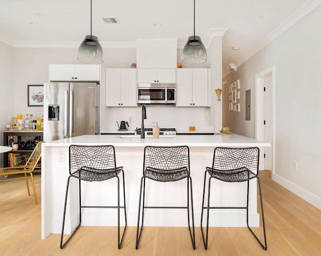 kitchen featuring appliances with stainless steel finishes, a breakfast bar, white cabinets, and light wood-style floors