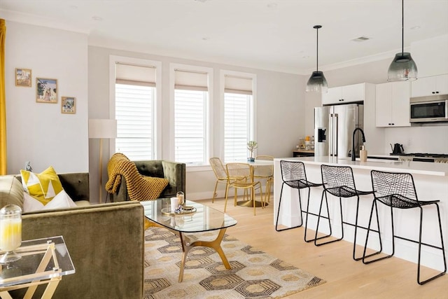 kitchen with light wood-style flooring, a breakfast bar, a sink, white cabinetry, and appliances with stainless steel finishes