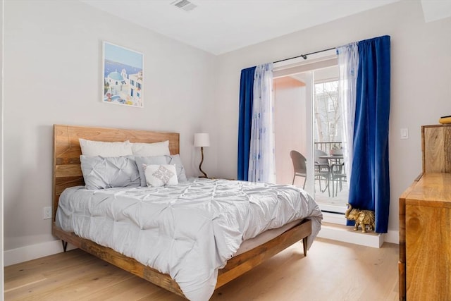 bedroom with baseboards, light wood finished floors, visible vents, and access to exterior