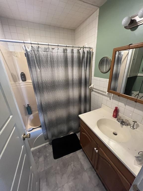 bathroom with tile walls, vanity, and shower / bath combination with curtain