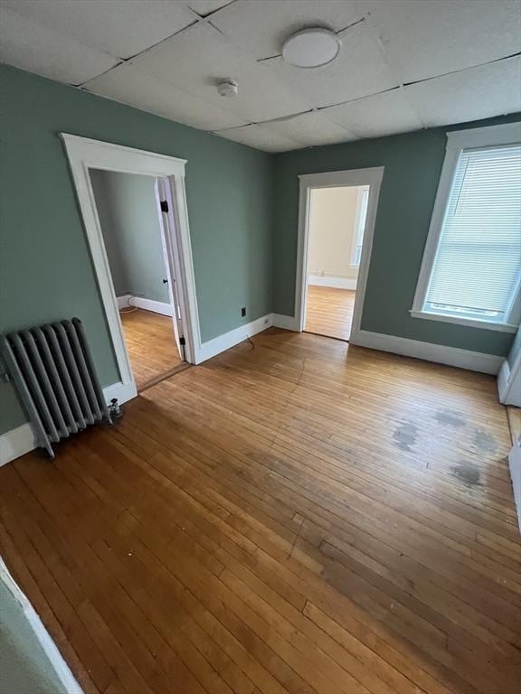 spare room with radiator, baseboards, and wood-type flooring