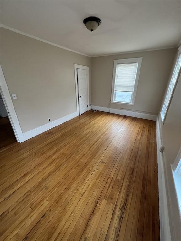 unfurnished room with wood-type flooring, baseboards, and ornamental molding