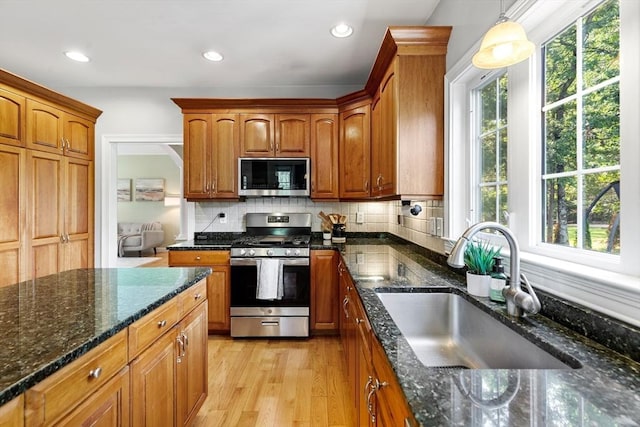 20 Hillside Dr, Georgetown, MA 01833 - kitchen with stainless steel appliances, dark stone countertops, brown cabinetry, backsplash, and light wood-style flooring